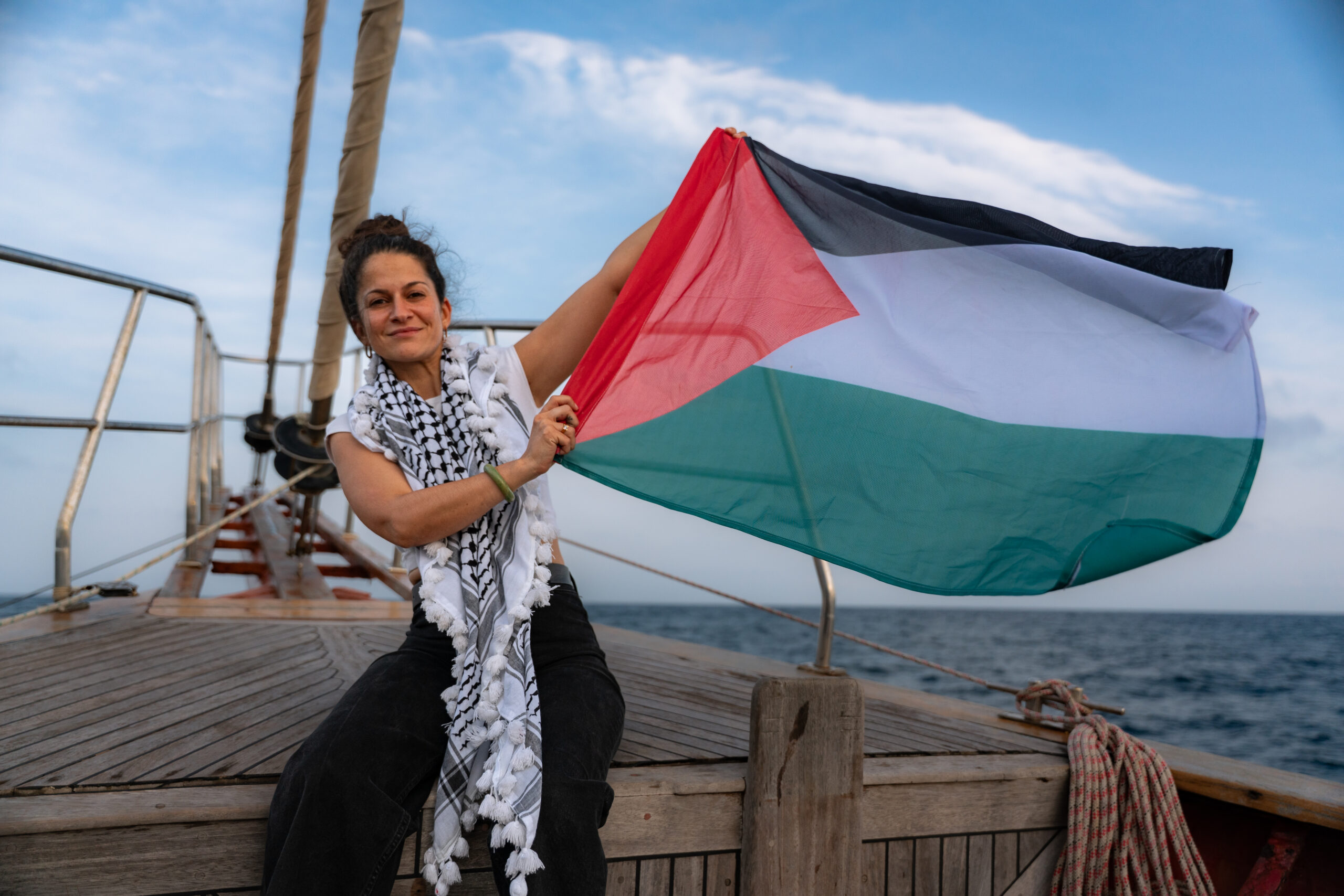 Woman aboard Global Sumud Flotilla, holding a Palestinian flag